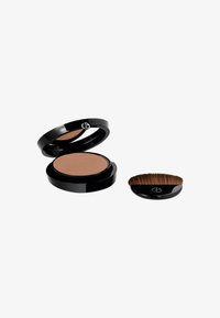 Bronzer compatto in una custodia nera con forma liscia e rotonda e un logo oro rosa. Include un pennello morbido e rotondo con setole fini.