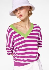 Striped short-sleeve top in purple and white, with a green V-neck collar. Soft material, loose fit, and mid-length sleeves.
