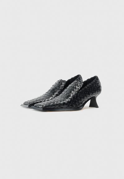 Scarpe in pelle intrecciata nera con punta appuntita e bordi scallopati. Presentano un tacco alto curvo e una superficie liscia.