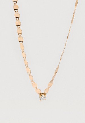Collier délicat en chaîne d'or avec un petit pendentif rond en pierre précieuse claire centré sur la chaîne sur un fond uni.
