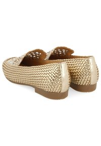 Mocasines tejidos en oro con un patrón texturizado, suela plana de goma y un diseño abierto en la parte superior para una mejor transpiración. Detalles metálicos suaves.