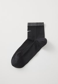 Chaussette de sport noire avec une partie supérieure texturée, un bout renforcé et un logo blanc sur le côté. Dispose d'un poignet côtelé pour un ajustement sécurisé.