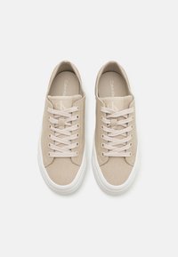Beige Leinensneaker mit weißen Gummisohlen, runder Spitze, klassischem Schnürdesign und dezenter Branding auf der Zunge.