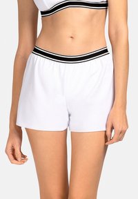 Białe sportowe spodenki z elastycznym pasem, z czarnymi paskami na górze. Gładka faktura i luźny krój.