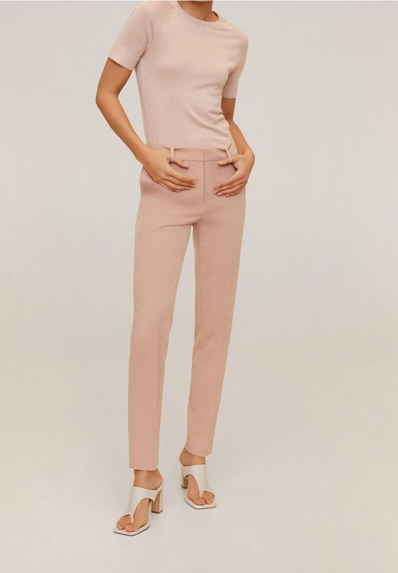Light pink short-sleeve top paired with light pink tailored pants. The model wears white heeled sandals with an open-toe design.