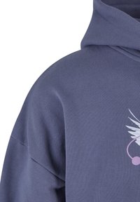 Hooded sweatshirt in dark blue fabric, featuring a white wing graphic with pink accents. Soft texture, loose fit with a large hood.