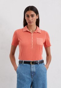 Korte mouw, collared polo shirt in koraal met een knoopsluiting aan de voorkant en een borstzak; katoen materiaal, zachte textuur, casual pasvorm.