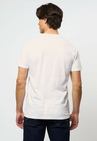 Valkoinen puuvillapaita, jossa on pyöreä pääntie ja lyhyet hihat. Paidassa on sileä rakenne ja normaali istuvuus. Takakatsaus ei sisällä graafisia kuvastoja tai kuvioita.