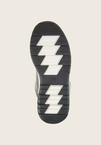 Suela de zapato negra con un patrón texturizado y tres acentos en zigzag blancos. Presenta una superficie estriada para mayor tracción. Diseño limpio y duradero.