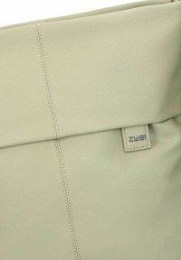 Bolso de cuero verde con un acabado texturizado, que presenta un diseño de solapa, costuras visibles y una etiqueta de marca integrada en el material.