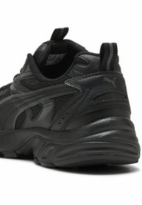 Schwarzer Sport Schuh mit einem strukturierten synthetischen Obermaterial, gepolstertem Schaft und gummierter Sohle, dezenten Markenzeichen und Netzelementen.