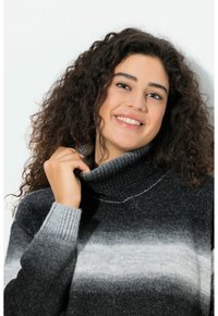 Neulottu pooloneule, jossa on liukuvärjätty mustan ja harmaan sävyissä, resorireunukset ja pehmeä koostumus.