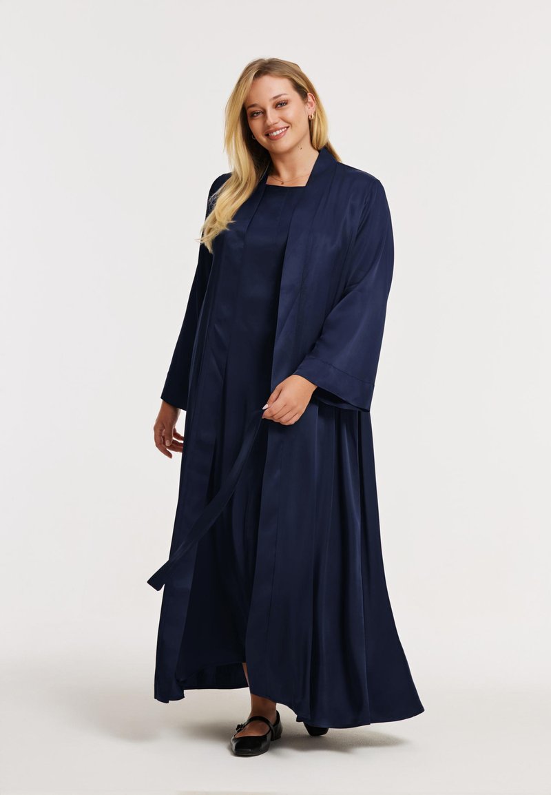 Robe longue en satin bleu marine avec manches kimono, dotée d'une taille cintrée et d'une jupe fluide. Comprend une ceinture assortie pour la fermeture.