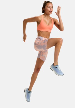 Athletic outfit featuring a pink sports bra and patterned, light-colored shorts. Light blue running shoes highlight the ensemble.