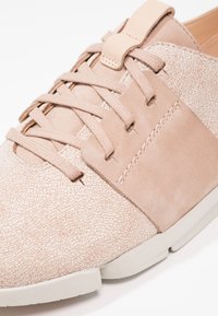 Basket beige avec embout texturé, panneaux latéraux en daim, lacets assortis et semelle en caoutchouc blanche segmentée.