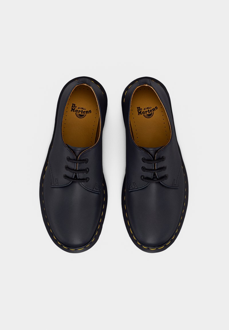 Scarpe oxford in pelle blu navy con punte arrotondate, caratterizzate da una texture liscia, lacci neri e cuciture gialle lungo la suola.