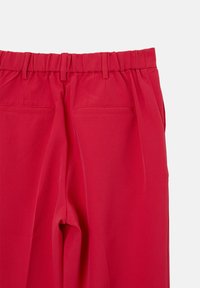 Rote maßgeschneiderte Hosen mit flachem Frontdesign, elastischem Bund und zwei Gesäßtaschen. Der Stoff wirkt glatt mit leichtem Glanz.