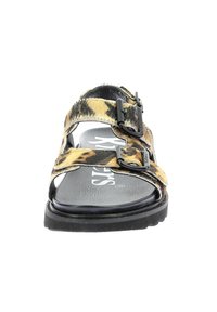 Sandalias de estampado de leopardo negro y amarillo con dos hebillas ajustables, una suela plana y una plantilla texturizada negra.