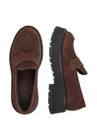 Mocasini din suede maro cu talpă din cauciuc negru cu branhii groase, o viziune pe partea de sus a unei încălțăminte și o viziune laterală, fără șireturi sau tablițe de călcâi.