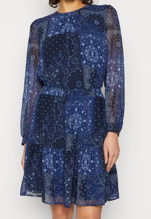 Robe bleu marine à manches longues, présentant un design en patchwork de motifs paisley et floraux. Fabriquée en tissu transparent avec une taille cintrée.