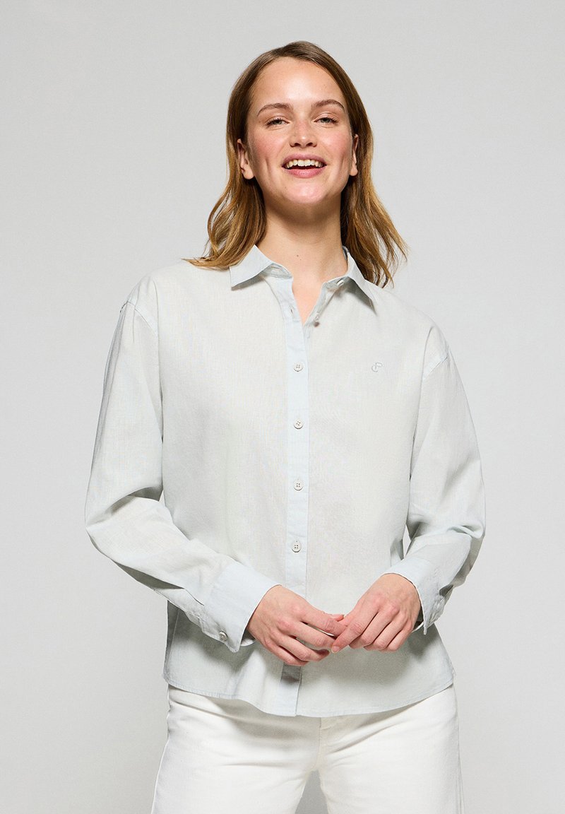 Ljusblå långärmad skjorta med knappslå och subtil textur. Har framknappar och en liten logotyp på bröstet.
