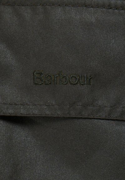 Тъмен зелен плат с гладка текстура, с извезано лого "Barbour" в съответстващ оттенък. Видимо детайлно зашито подгъване.