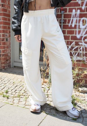 Vita cargobyxor med elastisk midja, med två sidofickor och en subtil logodetalj. Matchas med kraftiga vita sneakers.