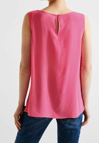 Ärmlös rosa blus med rund halsringning och en nyckelhålsdetalj på baksidan; tillverkad av mjukt tyg med en slät yta.