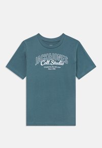 Mėlynas trumpomis rankovėmis marškinėliai su apvalia iškirpte. Priekinėje pusėje yra baltos spalvos užrašas "JACK&JONES Coll. Studio". Minkšta medvilnės tekstūra.