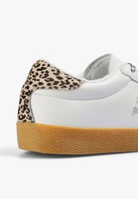 Zapatilla blanca con un talón de estampado de leopardo y una suela de goma texturizada. Presenta acentos en plata y un material similar al cuero suave.