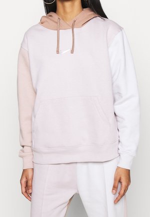 Lichtroze en witte hoodie met een grote voorkrui pocket en koordjes. Bevat een klein logo op de borst. Zachte textuur.