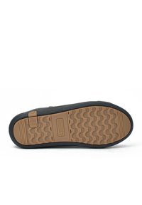 Suela de zapato de goma negra con un diseño texturizado. Presenta un área de goma marrón y una etiqueta de marca. Forma plana, diseñada para comodidad y durabilidad.