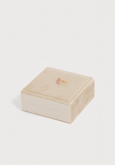 Μονό χρυσό σκουλαρίκι καρφί με ροζ οβάλ πολύτιμη πέτρα τοποθετημένο πάνω σε κλειστό μπεζ βελούδινο κουτί κοσμημάτων σε λευκό φόντο.