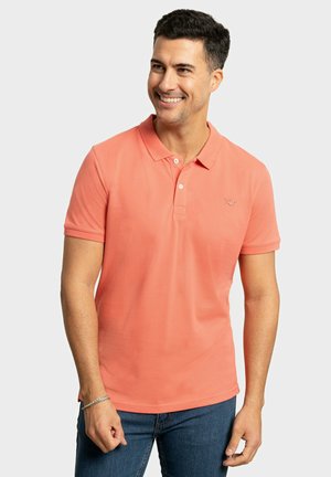 Camisa polo coral con cuello clásico, mangas cortas y una tapeta de tres botones. Presenta un pequeño logotipo en el lado izquierdo del pecho.