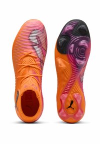 Scarpe da calcio arancioni e rosa con un upper testurizzato, dotate di tacchetti neri e viola, e un logo riflettente argento sul lato.