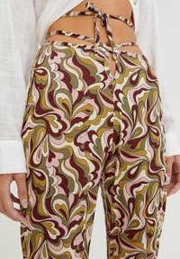 Wielokolorowe spodnie wzorzyste z kwiatowym motywem w oliwkowym, różowym i burgundowym odcieniu, wykonane z lekkiego materiału, z wiązanym pasem i wycięciem.