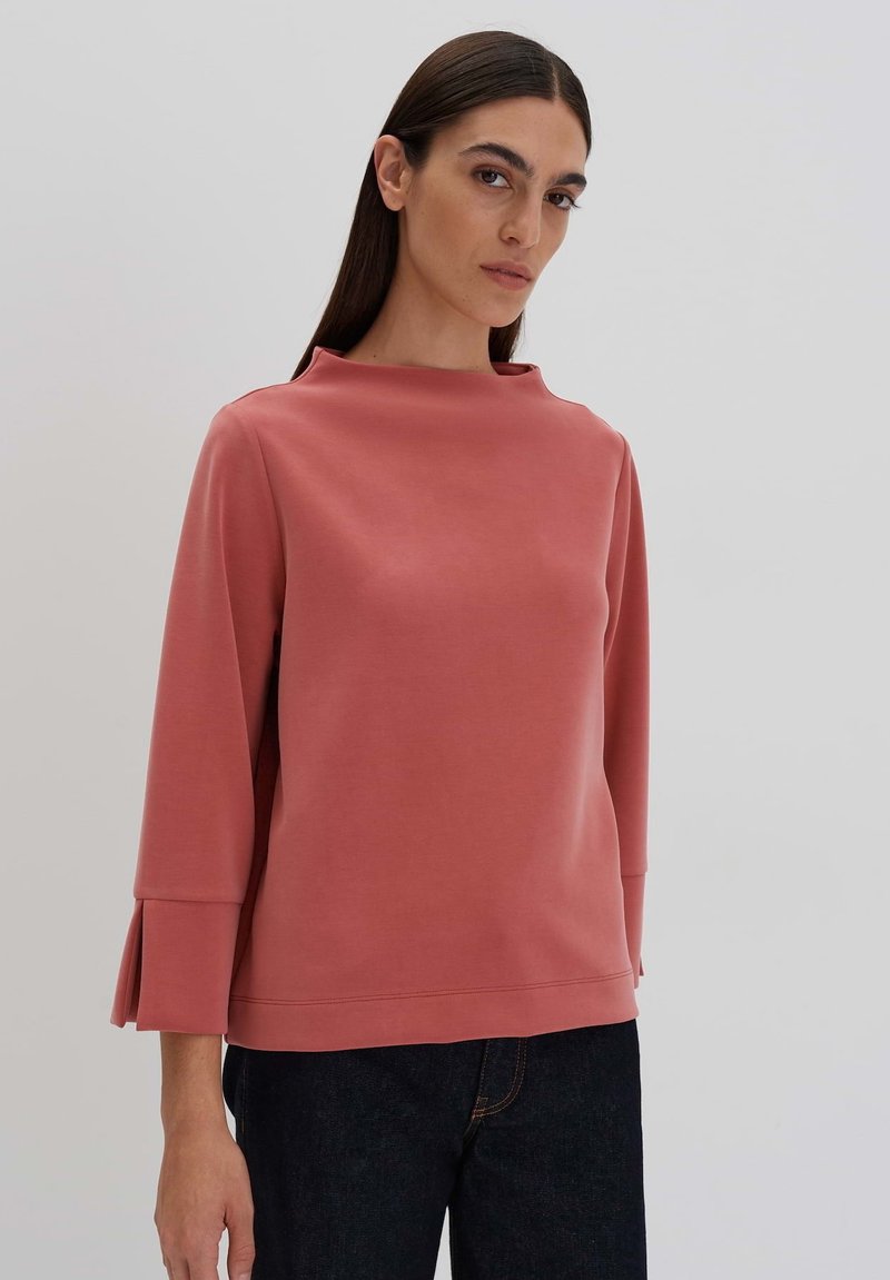 Rosé-pink Sweatshirt mit hohem Kragen und Dreiviertelärmeln, mit gefältelten Details an den Bündchen, aus weichem Stoff gefertigt.