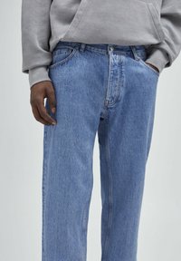 Jeans in denim blu chiaro con una vestibilità rilassata, caratterizzati da gamba dritta, design a cinque tasche e dettagli di cucitura sottili.