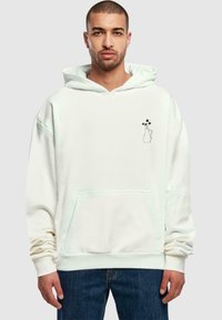 Weißer Kapuzenpullover aus Stoff mit einer Vordertasche. Mit einem einfachen schwarzen Umriss einer Vase mit Blumen auf der linken Brust. Lässige Passform.