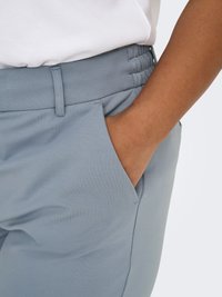 Light blue trousers made of soft fabric, featuring an elastic waistband and side pockets. Smooth texture with a fitted design.