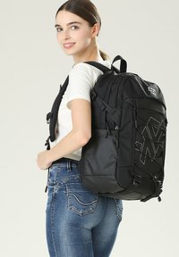 Zaino nero dal design elegante, con più scomparti, spallacci regolabili e dettagli in corda elastica per una maggiore praticità.