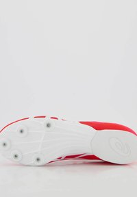 Scarpa sportiva rossa con superficie testurizzata, suola bianca e molteplici tacchetti per la trazione. Presenta un design snodato e accenti a contrasto.