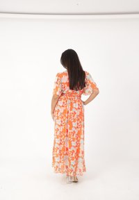 Robe maxi avec un motif floral en orange, rose et bleu clair. Caractéristiques des manches courtes et une taille cintrée, fabriquée en tissu léger.