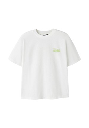 T-shirt blanc à manches courtes avec col rond et petit texte vert « Dresden CALIFORNIA » sur le côté gauche de la poitrine.