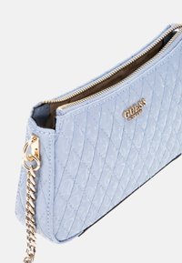 Sac à main matelassé bleu clair avec quincaillerie dorée, doté d'une fermeture à glissière et d'une chaîne en bandoulière. Le matériau est texturé et synthétique.