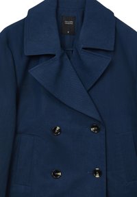 Manteau bleu marine à double boutonnage en tissu texturé avec un large col, comportant des boutons noirs et une poche plaquée. Étiquette indique "COLLECTION CALLIOPE S."