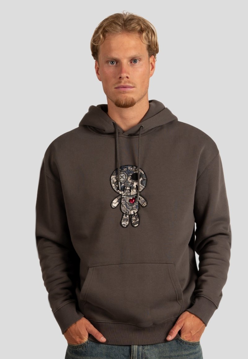 Grauer Hoodie mit einer Fronttasche und Kordelzugkapuze, mit einem bunten Patch-Design eines Cartoon-Charakters auf der Brust.