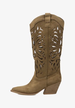 Bota de vaquero de gamuza color canela con borde festoneado, patrones florales cortados con láser, punta puntiaguda y tacón apilado inclinado.