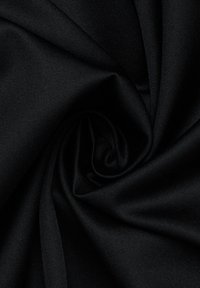 Tessuto nero con una superficie morbida e liscia, disposto a spirale. Presenta una leggera lucentezza con un colore uniforme e consistente.