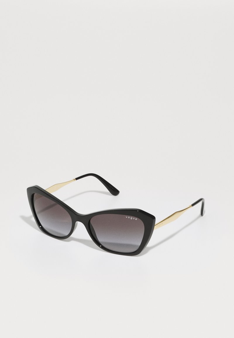 Óculos de sol pretos em formato de olho de gato com lentes degradê. Acessórios em tom de ouro nas hastes. Armação de plástico suave com um acabamento brilhante.